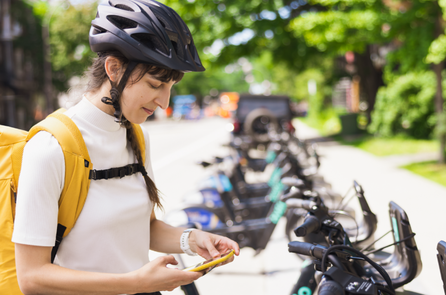 Women in bike helmet using bike share on mobile phone